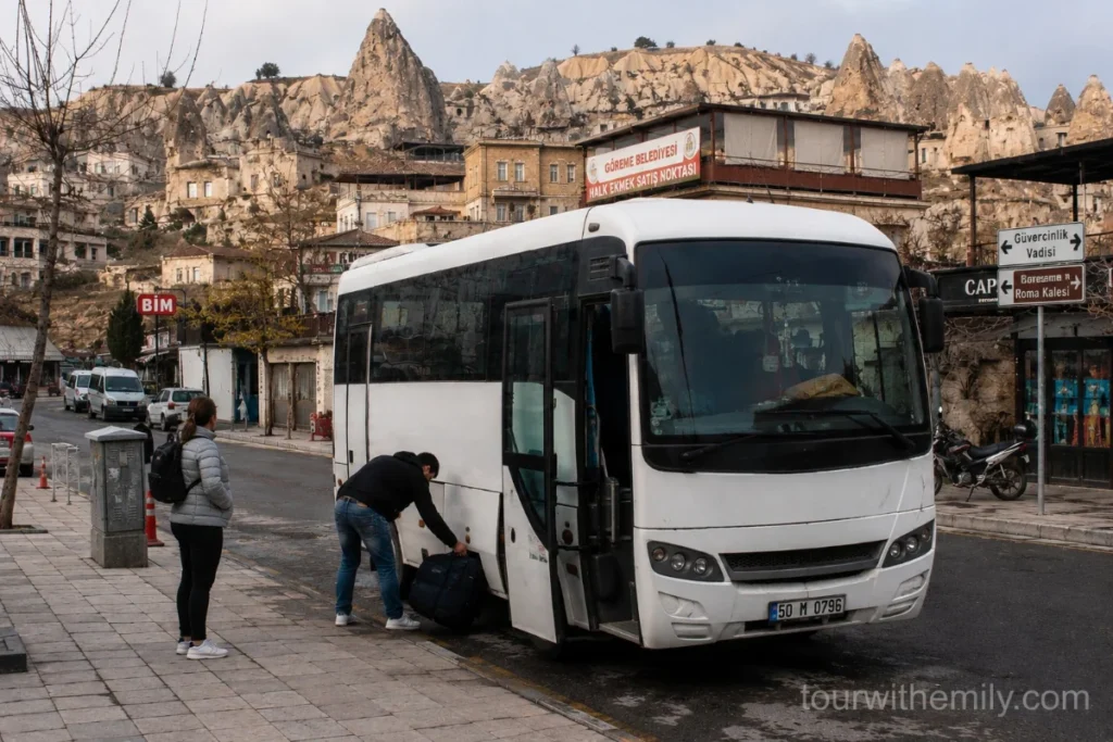 Small minibus dolmus parked in Göreme town center Cappadocia with cave rock formations in background