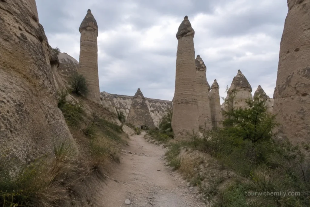 Narrow trail through Love Valley Cappadocia with tall phallic fairy chimney rock formations rising from the valley floor