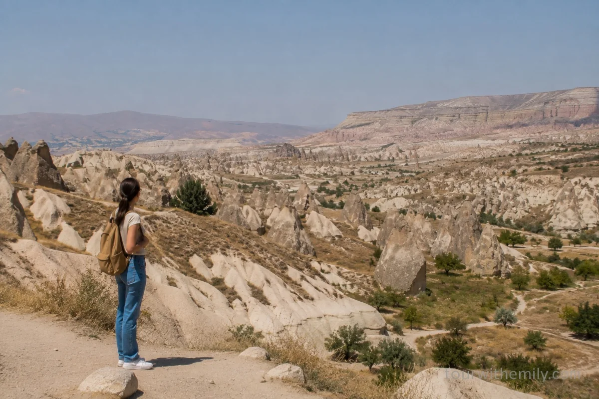 Solo female traveler standing on a hillside in Cappadocia Turkey looking out over fairy chimneys and valleys