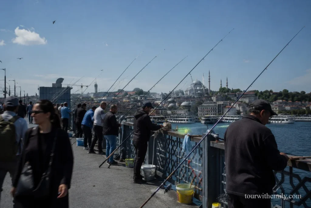 Fishermen lining the upper rail of Galata Bridge Istanbul with fishing rods over the Golden Horn and the Sultanahmet skyline in the background