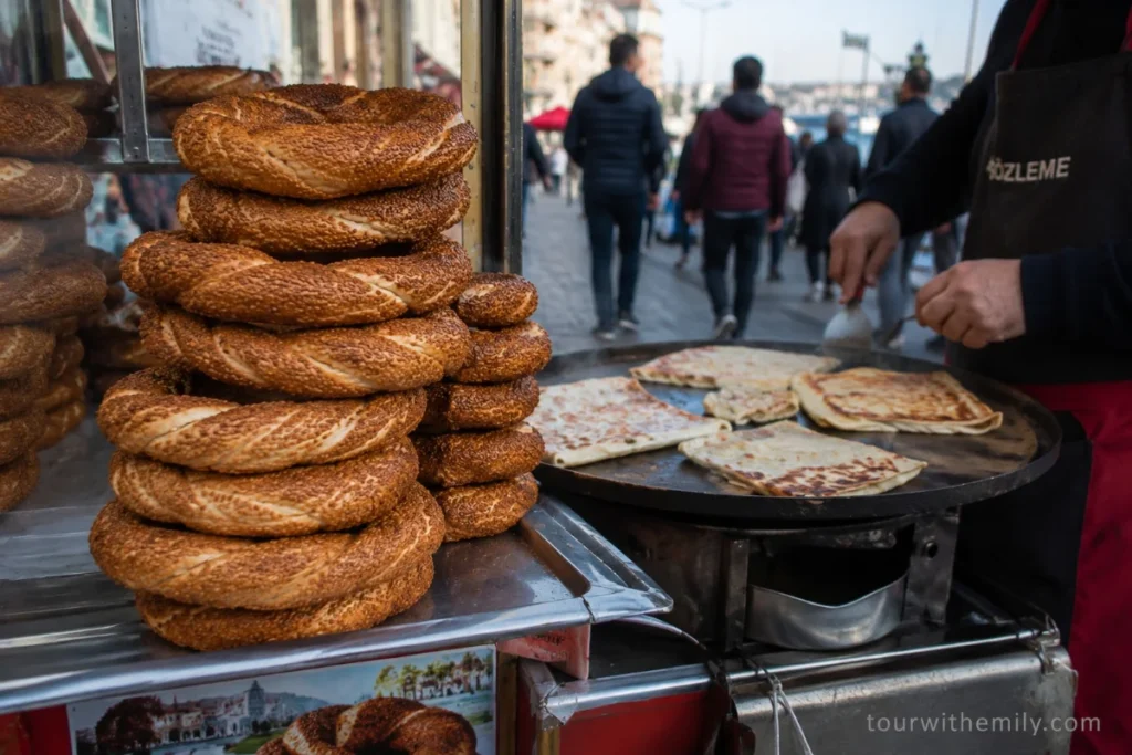Istanbul street food stall with simit sesame bread rings and gözleme flatbread being cooked on a griddle