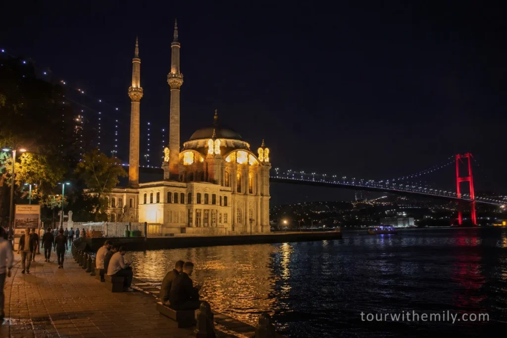 Ortaköy Mosque on the Istanbul waterfront at night with the illuminated Bosphorus Bridge in the background